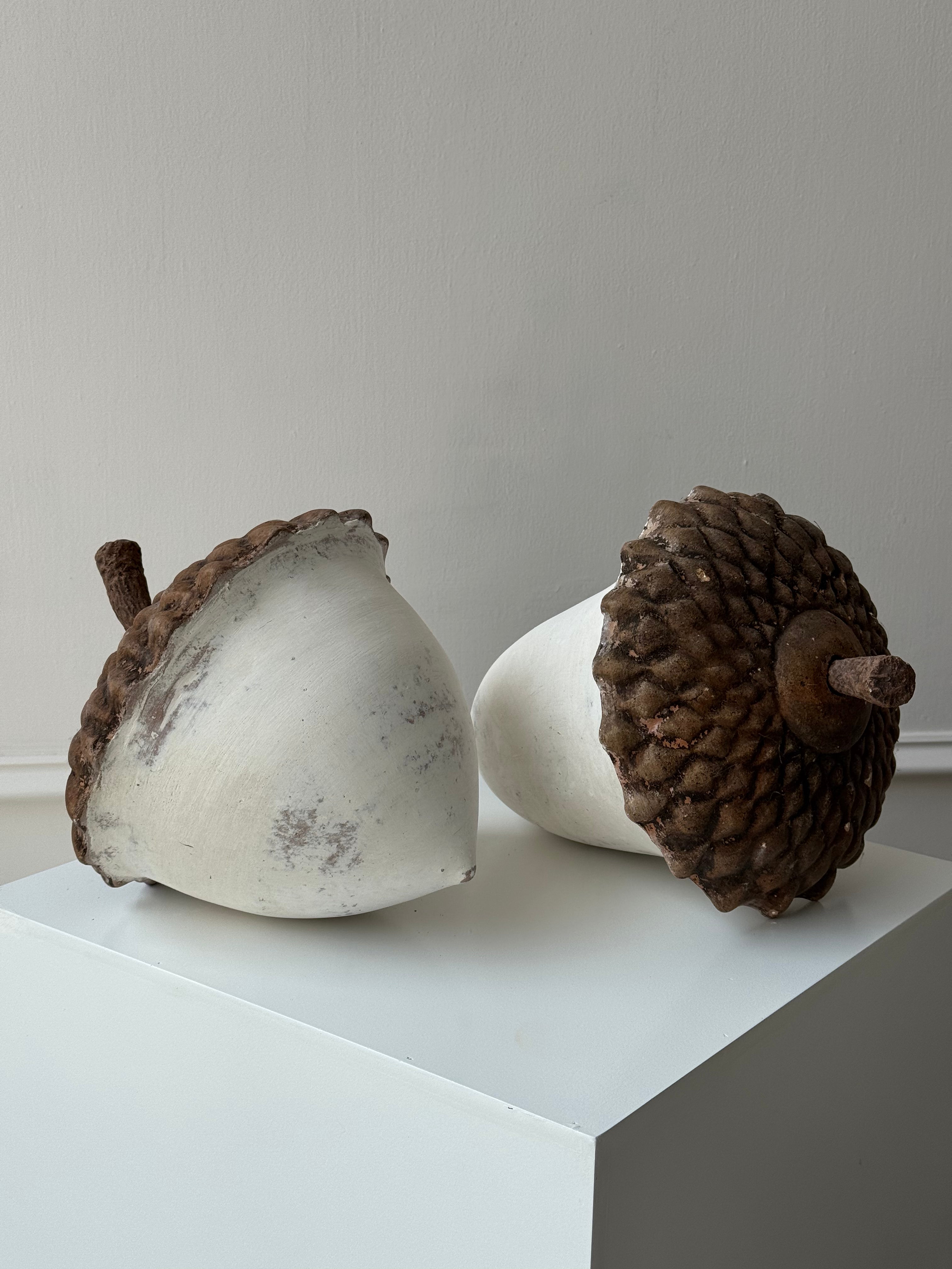 Par de bellotas grandes de barro artesanal con cabeza café y cuerpo blanco, ideales para decoración cálida y natural.
