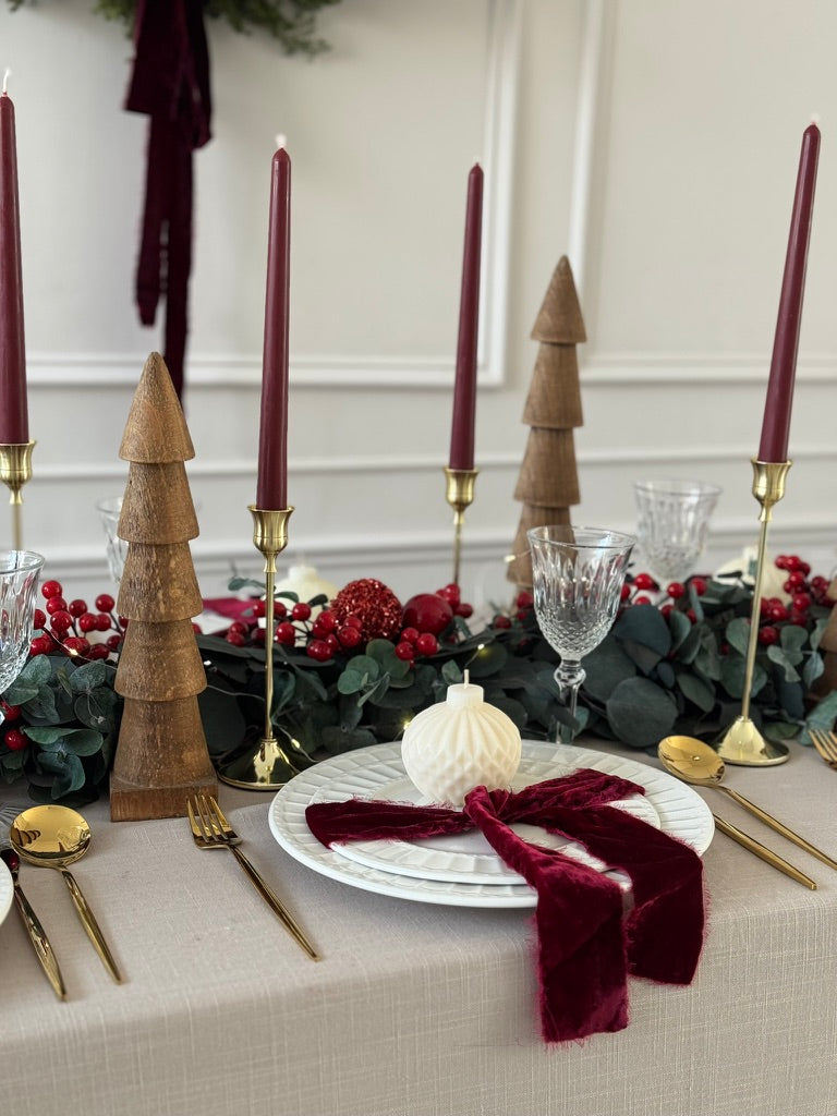 Camino navideño de eucalipto preservado con detalles rojos y cerezas artificiales.