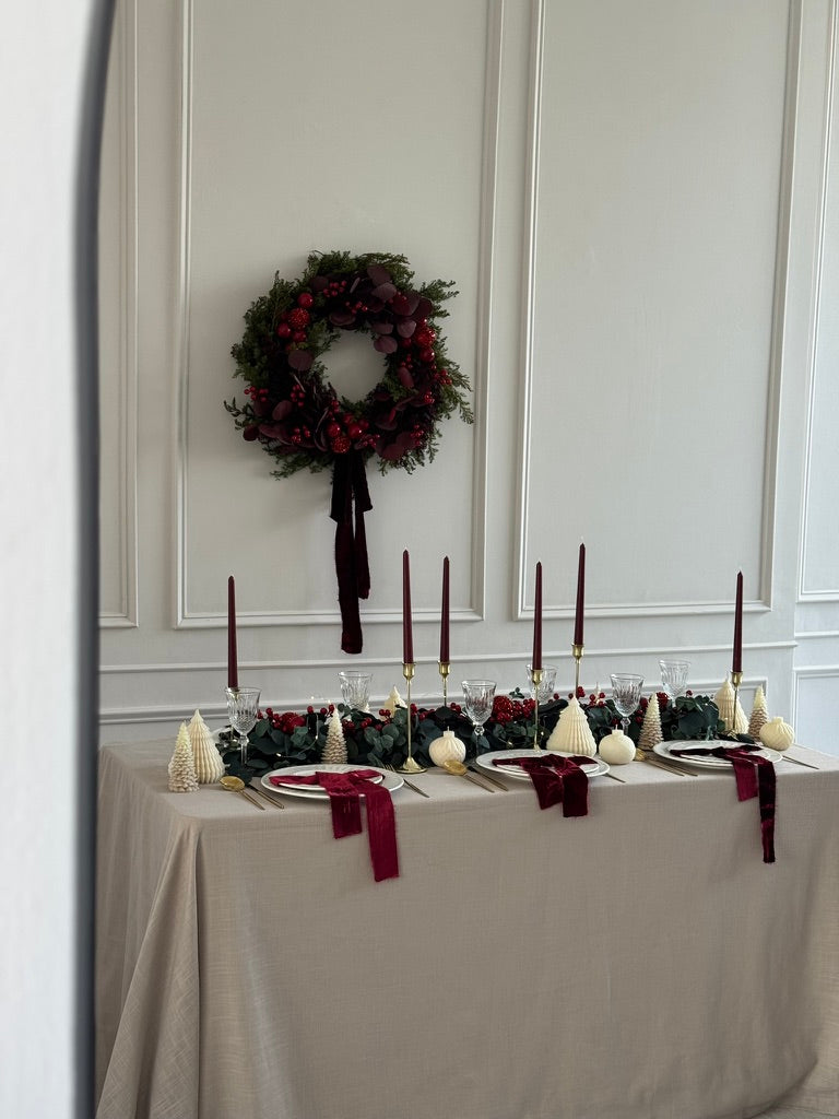 Decoración de mesa navideña con eucalipto y esferas rojas.