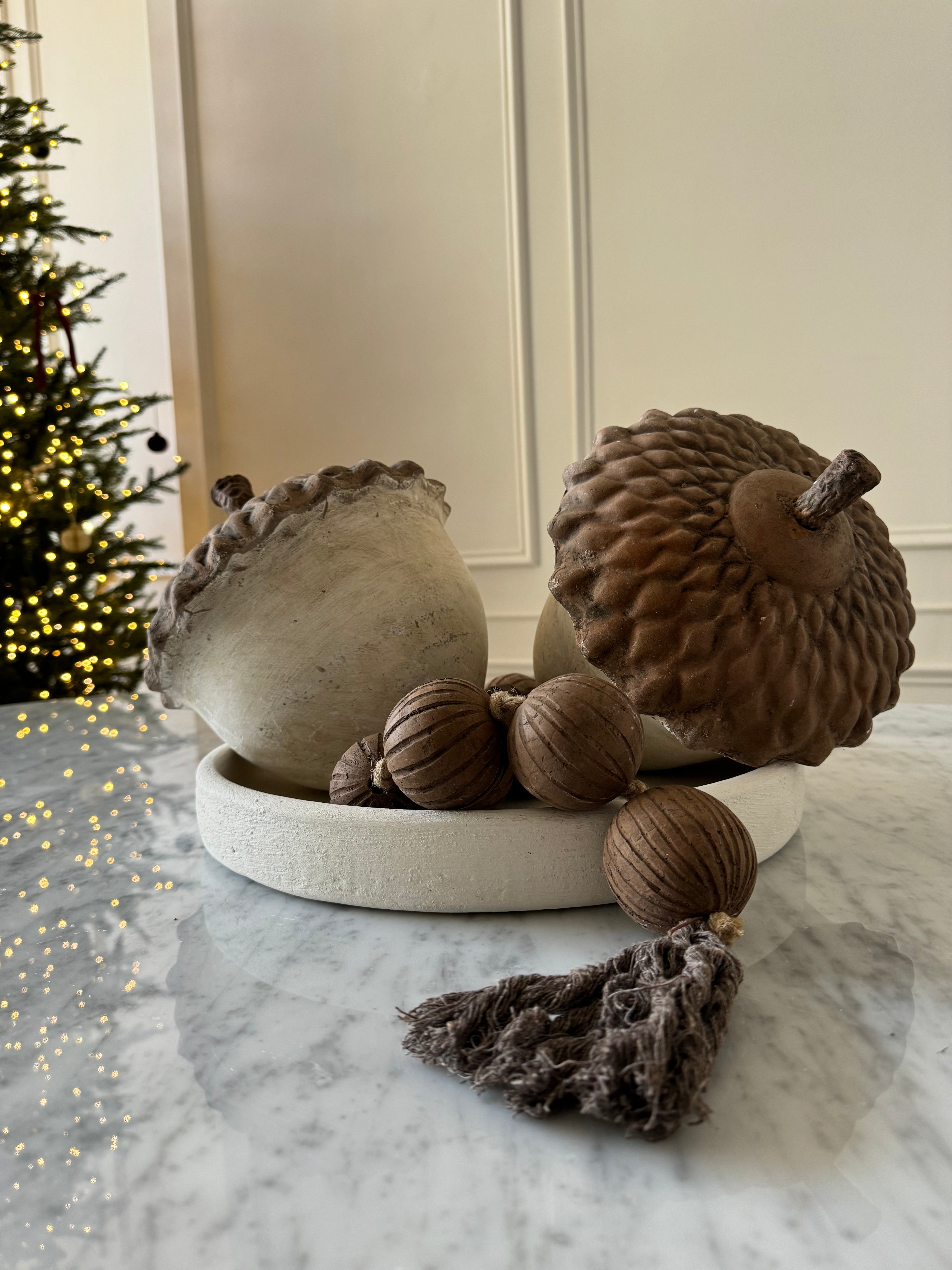 Par de bellotas grandes hechas de barro artesanal en tonos café y blanco perfectas para decoración rústica y de temporada.
