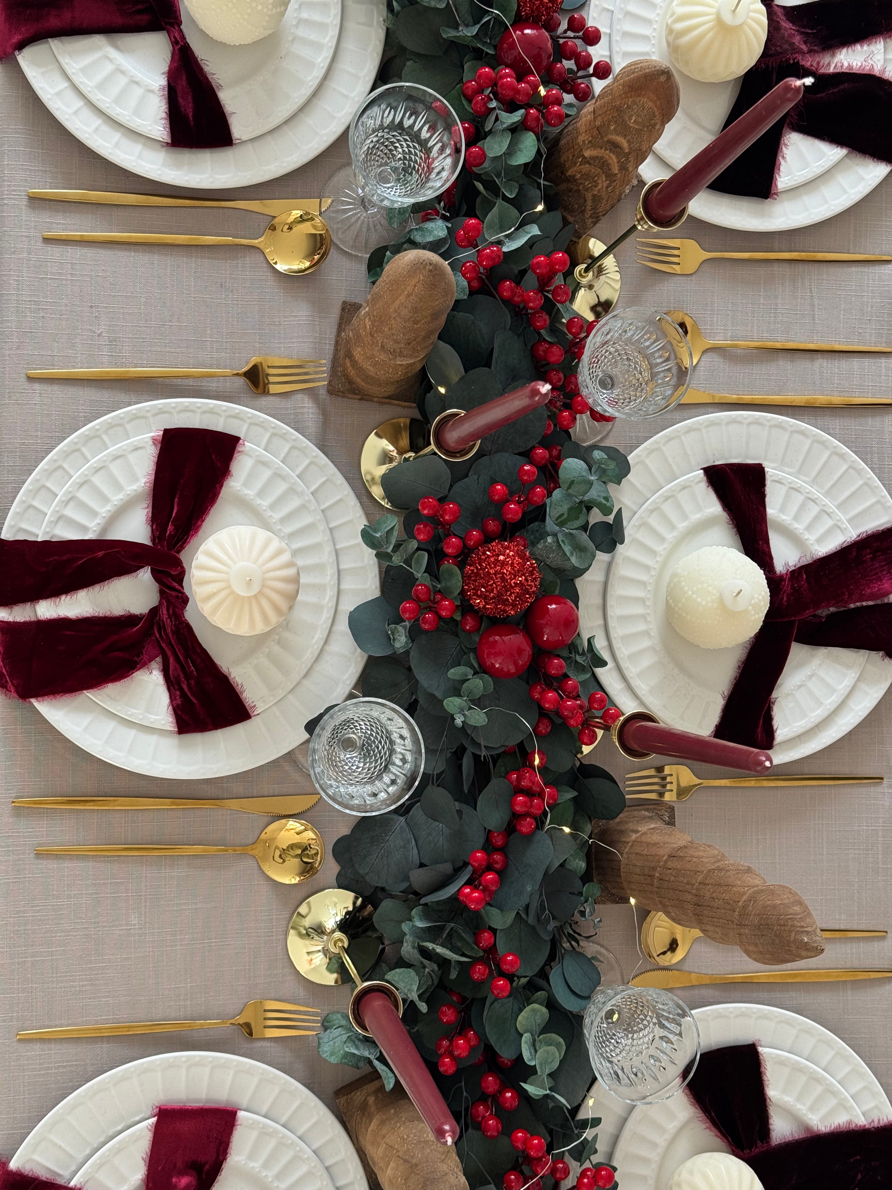 Camino de mesa navideño de eucalipto dólar con adornos rojos cherry.