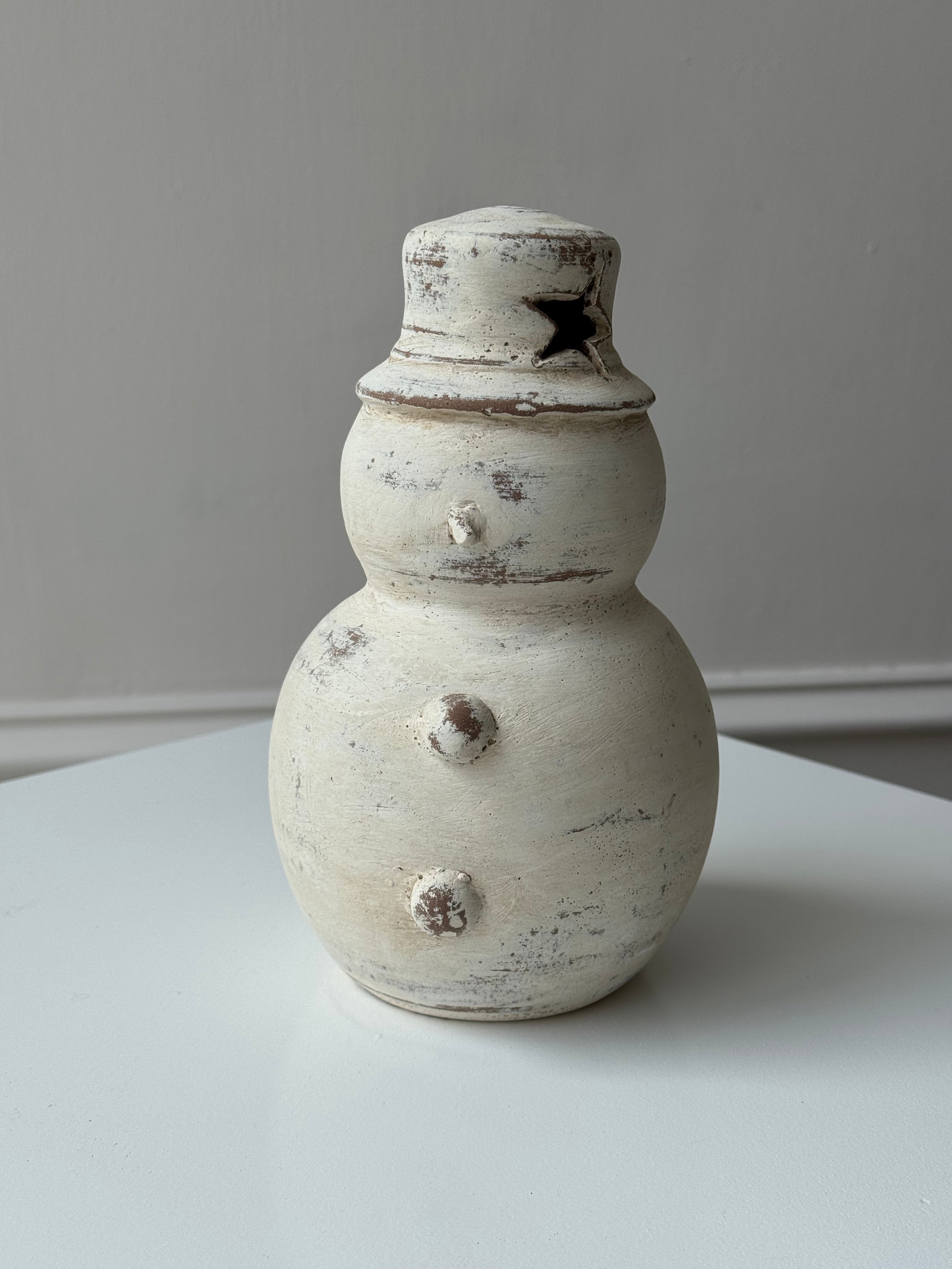 Figura de muñeco de nieve de dos bolas en barro blanco artesanal con sombrero.
