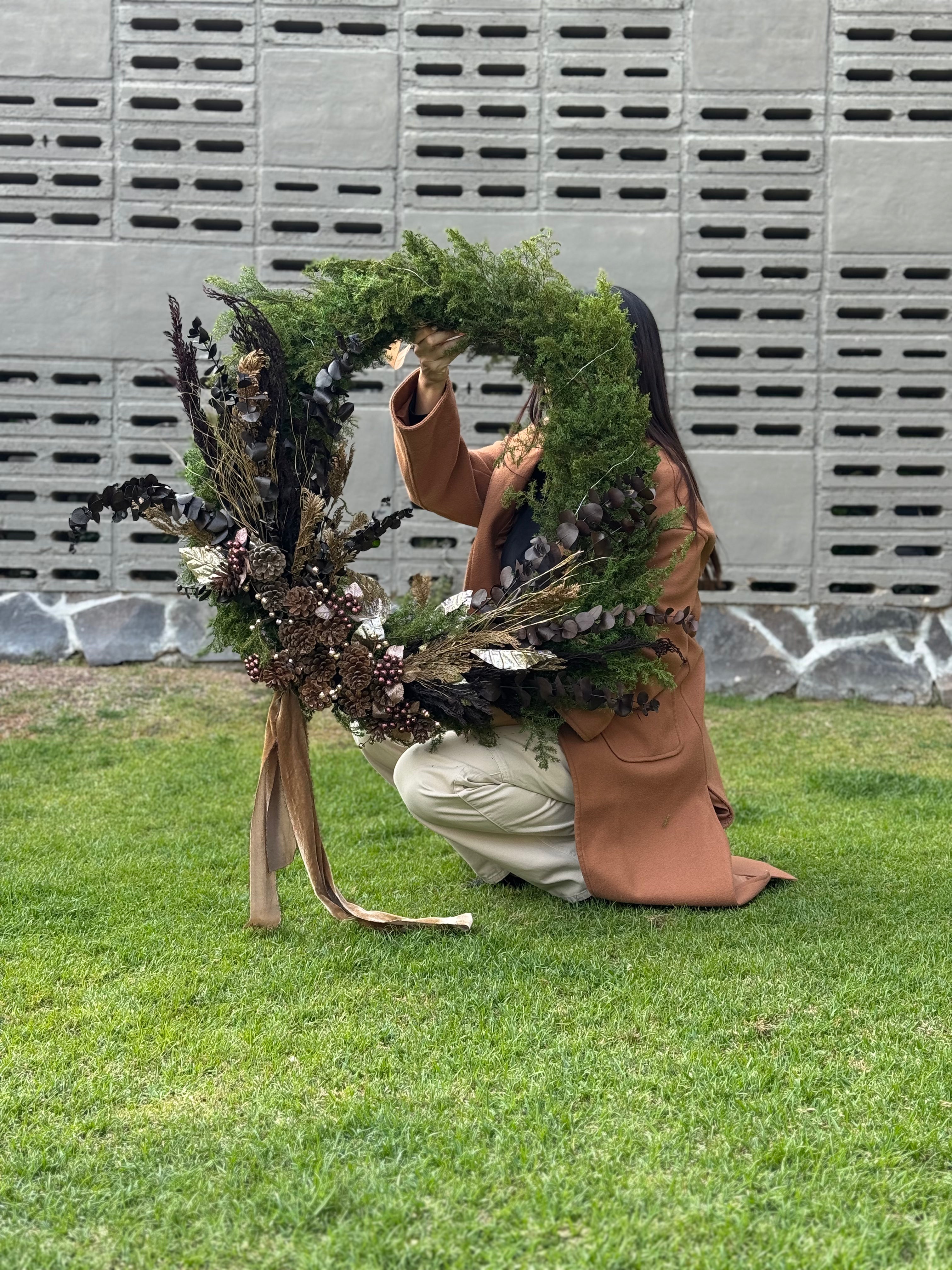 Corona grande de Navidad con pino verde, eucalipto preservado, piñas naturales y listones dorados.