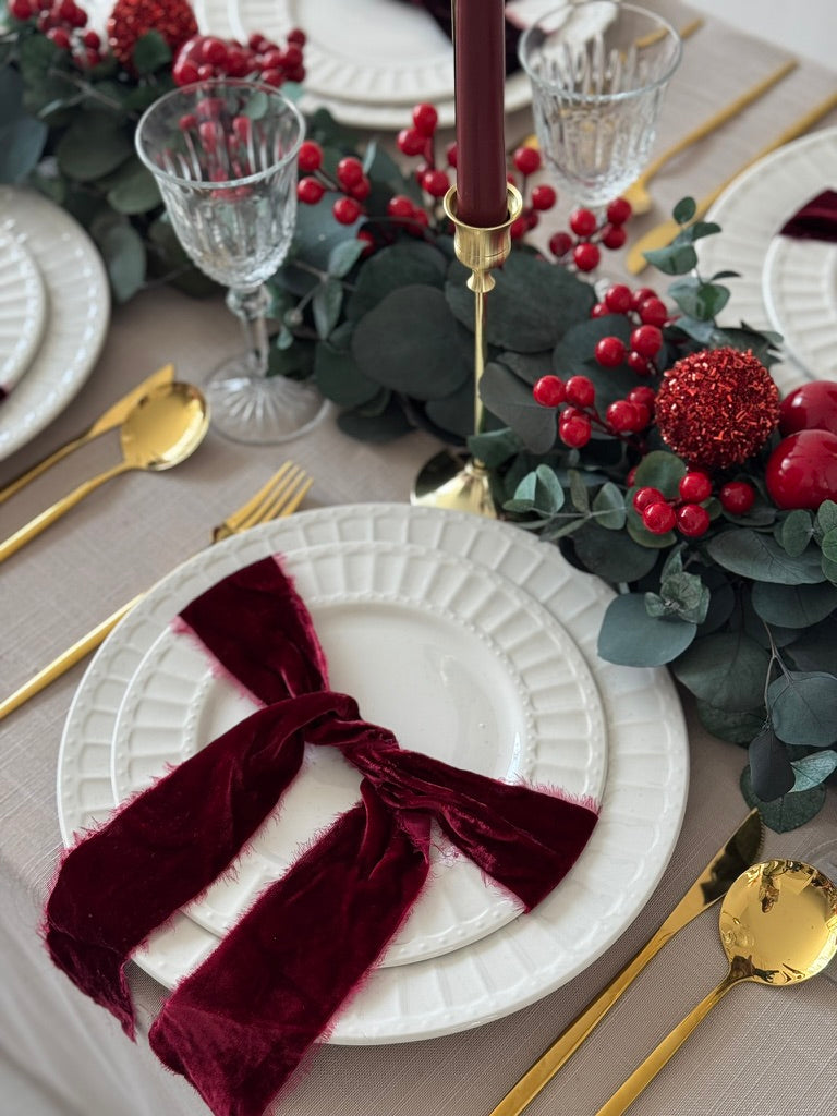 Camino de mesa hecho con eucalipto y cerezas rojas para decoración navideña.