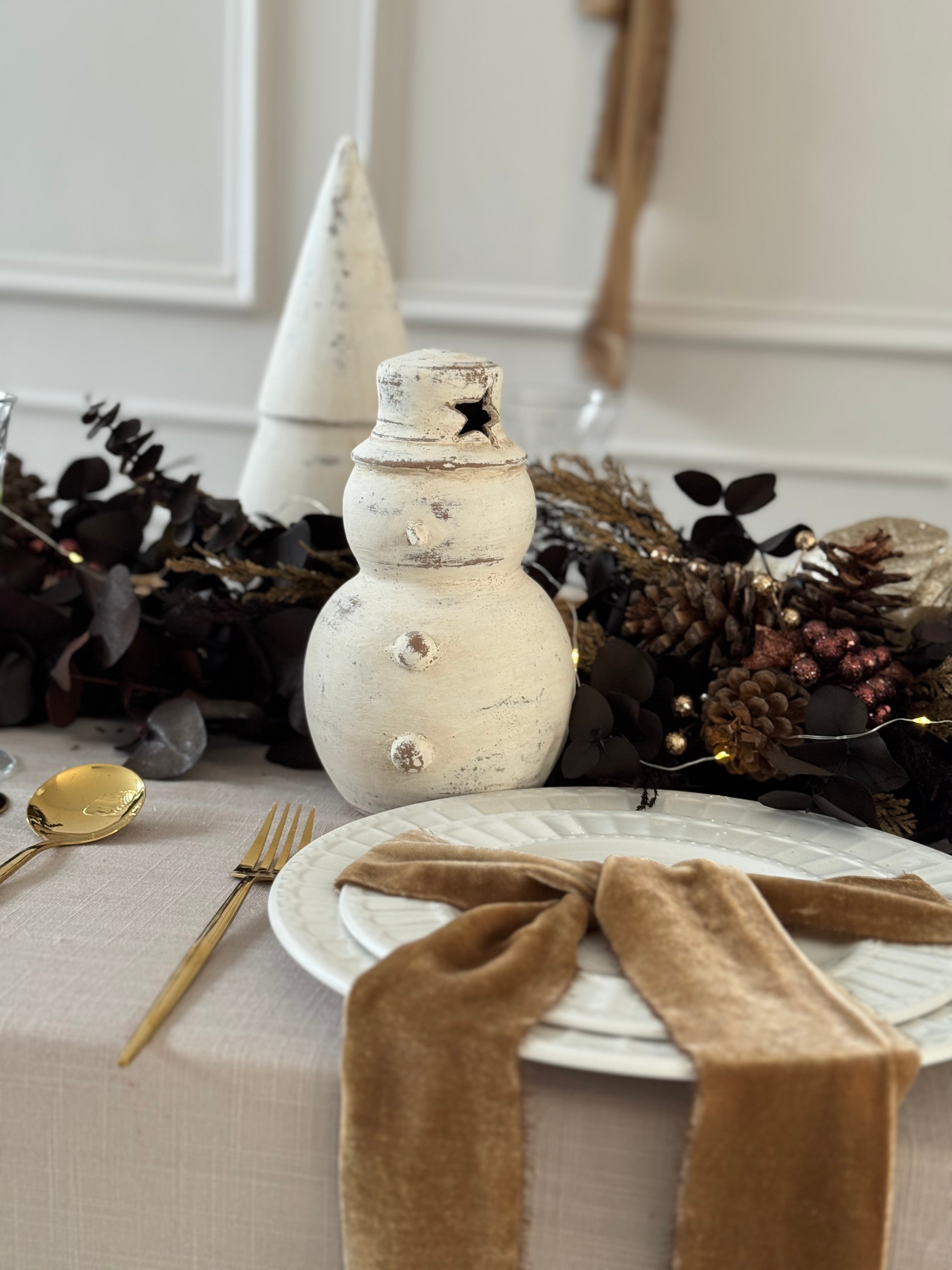 Muñeco de nieve hecho a mano en barro blanco con sombrero, decoración navideña.
