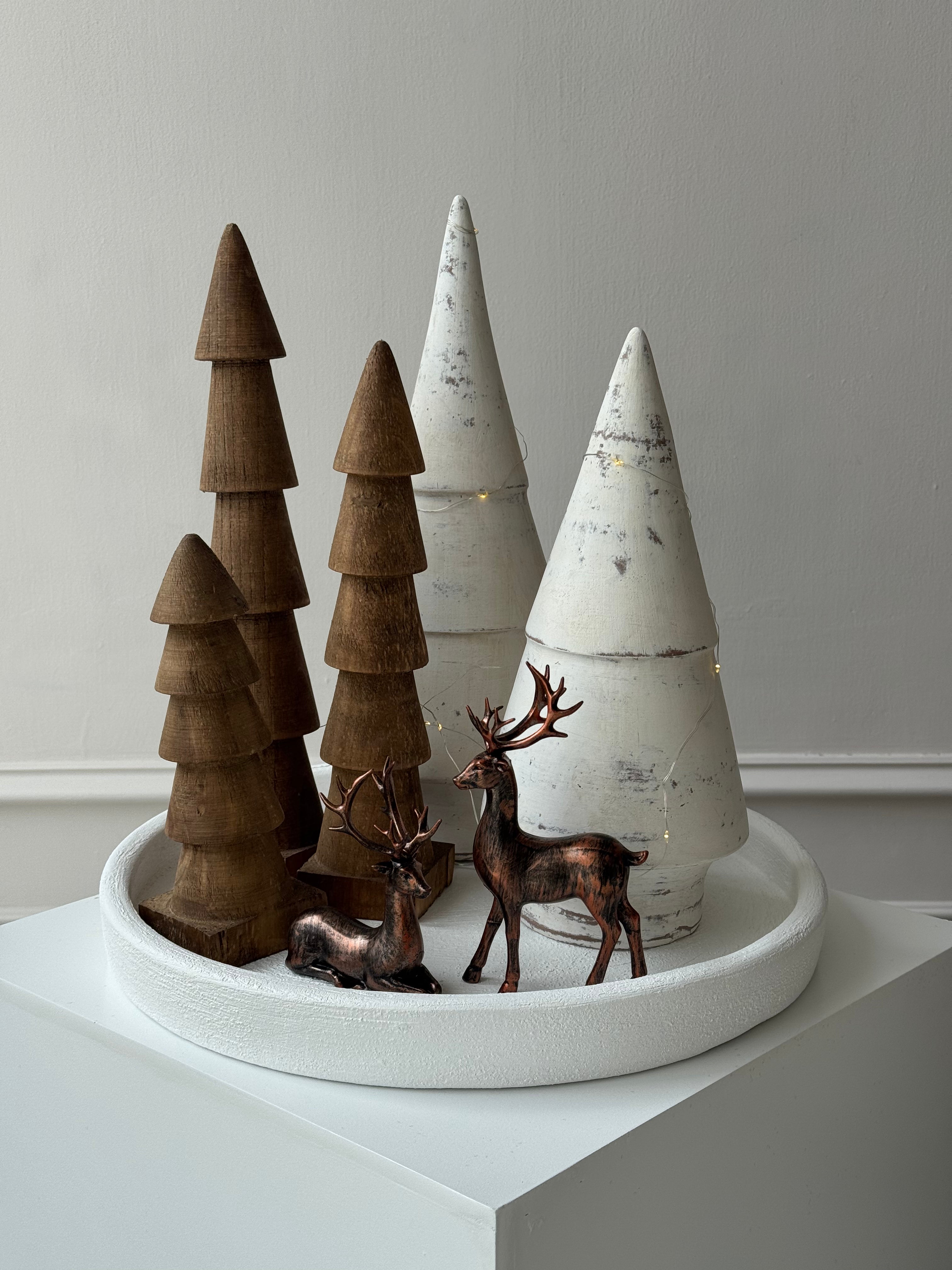 Pinos decorativos de madera en tres alturas distintas, tonos café o blanco, ideales para un ambiente limpio y moderno.
