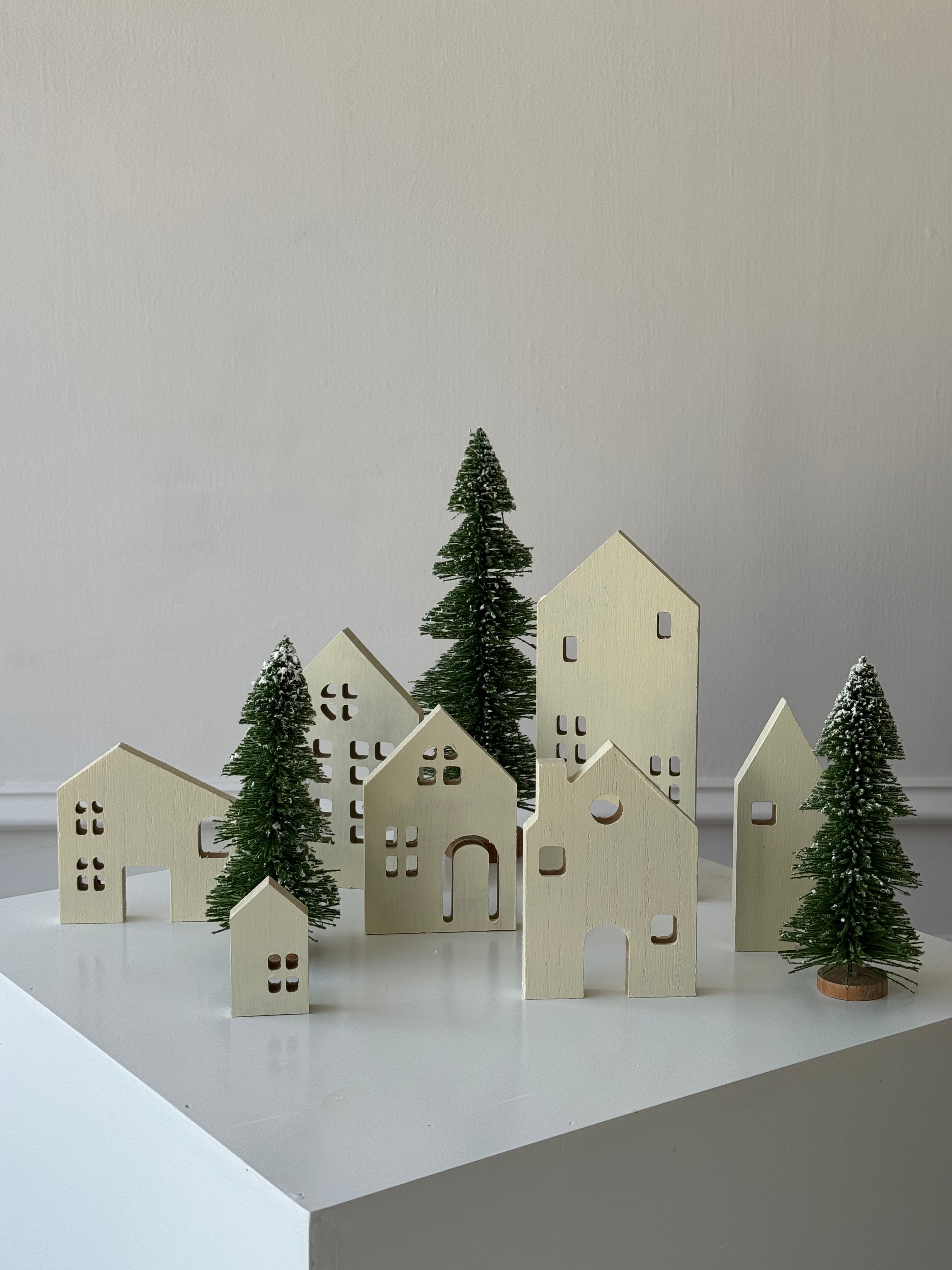 Set de siete casitas de madera que forman una villa navideña decorativa, perfecta para crear ambientes cálidos y festivos.
